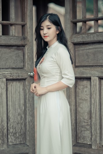 Woman Wearing White Dress in Middle of Two Brown Wooden Doors
