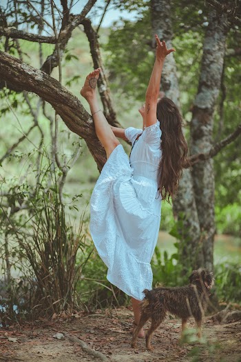 Woman Wearing White Dress Puts Her Left Leg on Tree Beside Dog