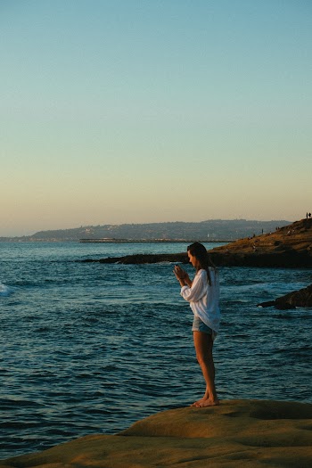 Woman Wearing White Dress Shirt Standing on Cliff