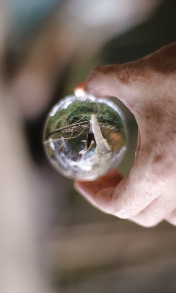 Woman Wearing White Dress Sitting on Slab Near Body of Water on Lens Ball Photography
