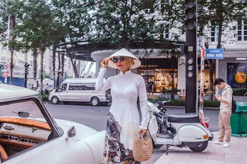 Woman Wearing White Dress Standing at Side of a Vehicle Parked at a Curb