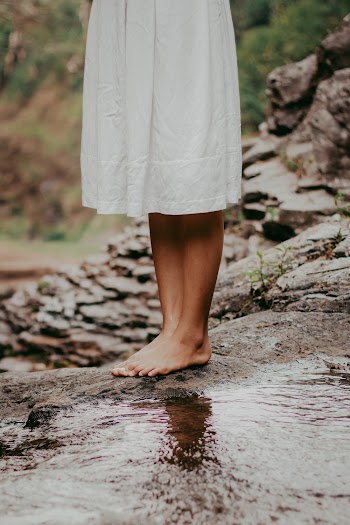Woman Wearing White Dress Standing Barefoot on Rock