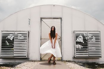 woman wearing white dress standing in front of white enclosure during daytime