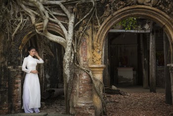 Woman Wearing White Long-sleeved Long Dress Standing at Arch