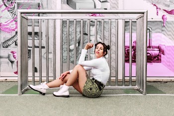 Woman Wearing White Long-sleeved Shirt and Green and Black Bottoms Sitting on Concrete Surface