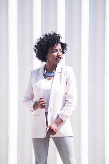 woman wearing white notched-lapel blazer and grey fitted jeans