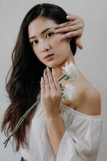 Woman Wearing White Off-shoulder Blouse Holding White Rose Flower While Touching Her Hair