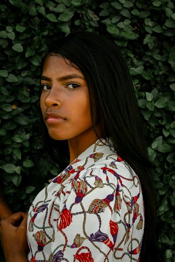 Woman Wearing White, Red, and Brown Floral Top Posing Sideways