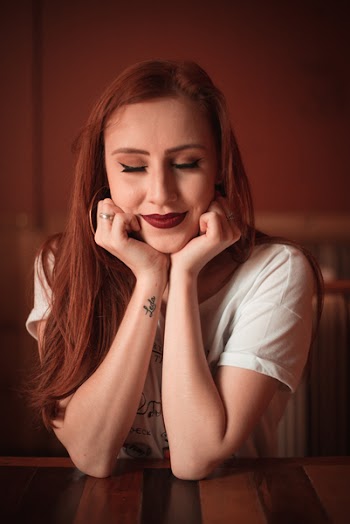 Woman Wearing White Scoop-neck T-shirt With Elbow Leaning on Table Top