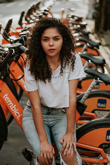 Woman Wearing White Shirt and Blue Denim Jeans Standing Near Bicycles