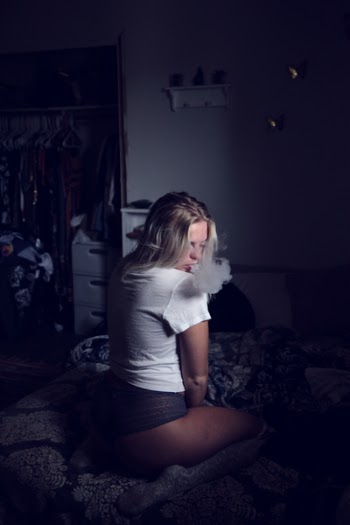 Woman Wearing White Shirt Sitting on Sofa and Smoking