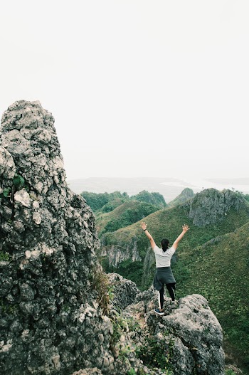 Woman Wearing White Shirt Standing on Rock Formation