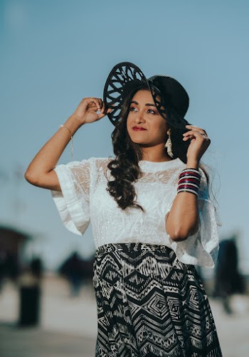 Woman Wearing White Short-sleeved Blouse Standing While Touching Her Black Hat