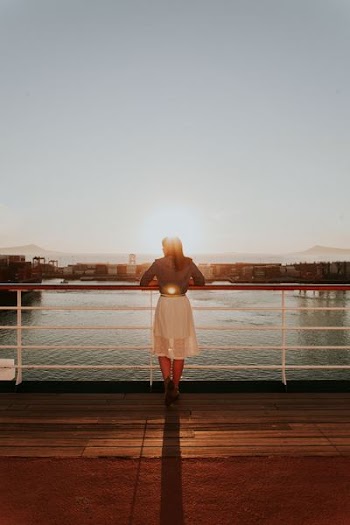 woman wearing white skirt looking at body of water during daytime