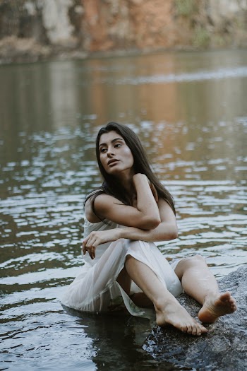 Woman Wearing White Sleeveless Dress Sitting Beside Body of Water