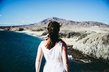 Woman Wearing White Sleeveless Dress Standing Near Blue Sea Under Clear Blue Sky