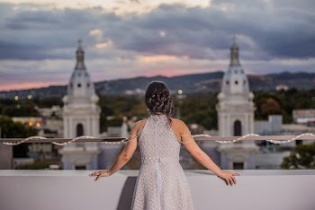 Woman Wearing White Sleeveless Dress Standing While Facing on White Tower Buildings Under White and Gray Sky