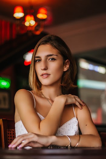 Woman Wearing White Spaghetti-strap Top Siting by the Table