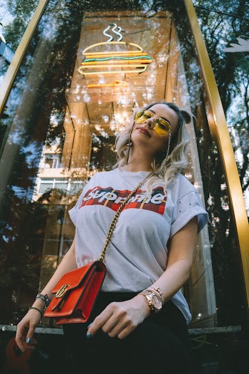Woman Wearing White Supreme Shirt Standing in Front of Glass Wall
