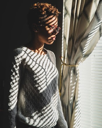 Woman Wearing White Sweater Standing Front of Window