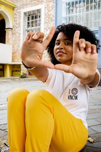Woman Wearing White T-shirt and Yellow Pants Sitting on Concrete Floor