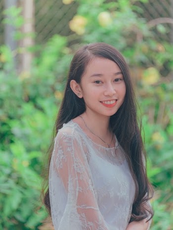 Woman Wearing White Tank Top Taking Picture Against Green Leaf Plant