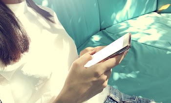 Woman Wearing White Top Holding Black Smartphone