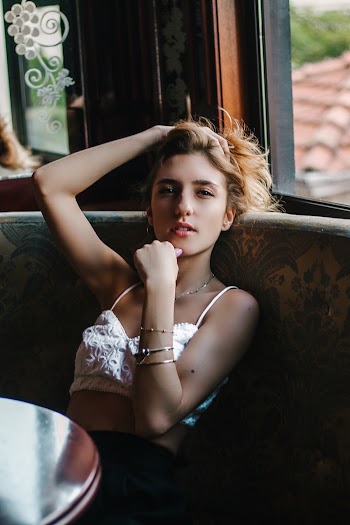 Woman Wearing White Top Leaning on Chair While Holding Chin
