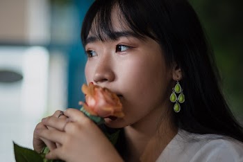 Woman Wearing White Top Smelling Pink Rose