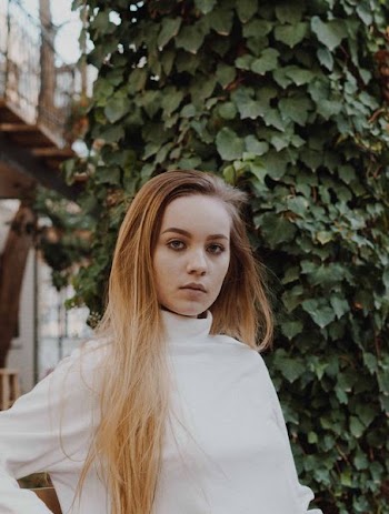 woman wearing white turtleneck shirt near green leafed plant