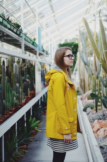 woman wearing yellow coat in front of plant