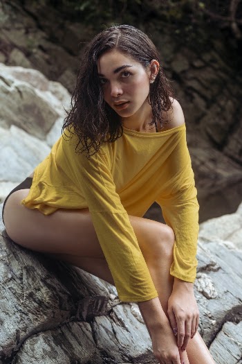 Woman Wearing Yellow Crew Neck T-Shirt While Sitting on Rock