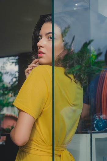 Woman Wearing Yellow Dress Leaning On Clear Glass Wall