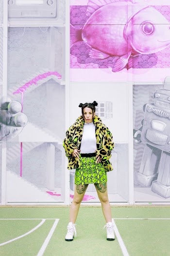 Woman Wearing Yellow-green and Black Jacket and Green Miniskirt Standing on Green and White Sport Field