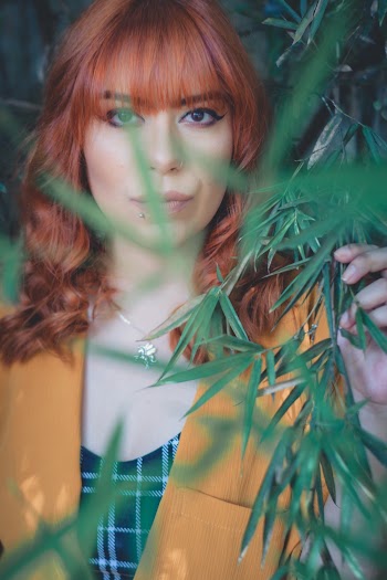 Woman Wearing Yellow Suit Jacket Holding Green Bamboo Leaves