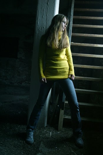 Woman Wearing Yellow Sweater Leaning on Wall