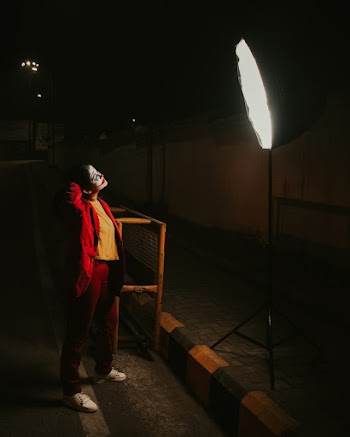 Woman Wearing Yellow Top and Red Jacket Looking at Softbox