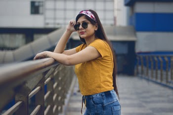 Woman wearing Yellow Top, Blue Jeans and Eyeglasses Leaning on Rails