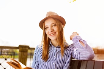 Woman Wears Black and White Striped Top Leaning on Brown Rail