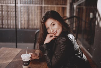 Woman Wears Black Leather Jacket Sits With Cup of Cold Beverage