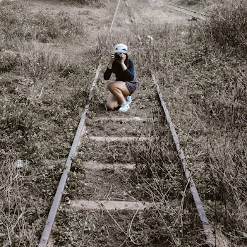Woman White Round Hat Holding Black Dslr Camera on Rail Way