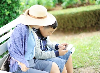 Woman With a Boy Sits on Bench
