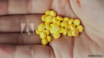 Woman with a handful of yellow pills