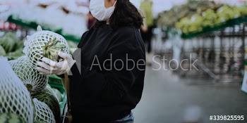 Woman with a medical mask buying fresh food during coronavirus pandemic