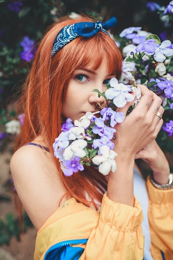 Woman With Bandana Smelling Purple And White Flowers