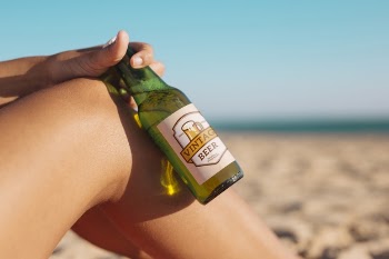 Woman with beer bottle mockup at the beach Free Psd
