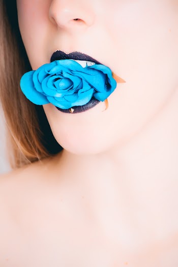 Woman With Black Lipstick Biting Blue Rose