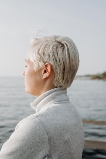 woman with blonde hair wearing gray sweater at dock