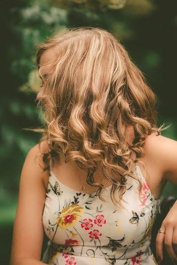 Woman With Curly Blonde Hair Wearing A White Floral Spaghetti Strap Dress
