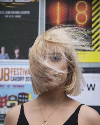 Woman With Flipping Hair Standing Near Poster